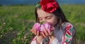 Bulgarian girl woman in ethnic folklore dress enjoying parfumery oil-bearing rose Rosa Damascena, Kazanlak, Bulgaria