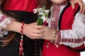 Bulgarian kids boy and girl in traditional folklore costumes with spring flowers snowdrop and handcraft wool bracelet martenitsa