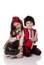 Bulgarian kids boy and girl in folklore clothes, spring snowdrops, flute, red white martenitsa March holiday Baba Marta, Bulgaria Royalty Free Stock Photo