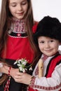 Bulgarian kids boy and girl in traditional folklore costumes with spring snowdrops, martenitsa symbol of Baba Marta