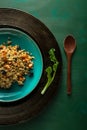 Bulgur pilaf with carrots and raisins on blue plate with wooden spoon and cillantro branch