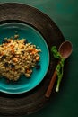 Bulgur pilaf with carrots and raisins on blue plate with wooden spoon and cillantro