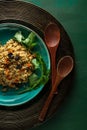 Bulgur pilaf with carrots and raisins on a blue plate with wooden spoons