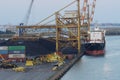Bulk cargo vessel moored in coal terminal in port of Venezia with cargo gantry cranes, pile of black coal.