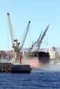 The bulk-carrier LAWIN ARROW loading cement with cranes in the port of Alicante. Royalty Free Stock Photo