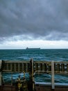 A bulk carrier ship passing under heavy rain clouds and storm clouds and rough weather Royalty Free Stock Photo