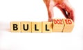Bull or bulldozed symbol. Businessman turns wooden cubes and changes word Bull to Bulldozed. Beautiful white table white
