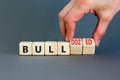 Bull or bulldozed symbol. Businessman turns wooden cubes and changes word Bull to Bulldozed. Beautiful grey table grey background