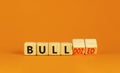 Bull or bulldozed symbol. Businessman turns wooden cubes and changes word Bull to Bulldozed. Beautiful orange table orange
