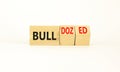 Bull or bulldozed symbol. Businessman turns wooden cubes and changes word Bull to Bulldozed. Beautiful white table white