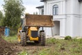 bulldozer is being prepared to demolish illegally built private house in natural area. Close up photo of tractor with bucket in Royalty Free Stock Photo