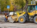 bulldozer with bucket and workers on asphalting and repair of city streets