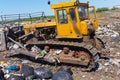 A bulldozer clears heaps of garbage in a garbage can. Work bulldozer in a landfill