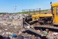 A bulldozer clears heaps of garbage in a garbage can. Work bulldozer in a landfill