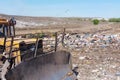 A bulldozer clears heaps of garbage in a garbage can. Work bulld