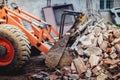 bulldozer demolishing a building and carrying debris into dumper trucks