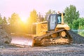 Bulldozer dredges rubble on road construction in the lights of morning sun Royalty Free Stock Photo