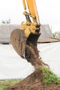 A bulldozer pours out a bucket of land on a construction site close-up. Excavation industrial work Royalty Free Stock Photo