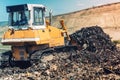 bulldozer pushing garbage and working on trash site