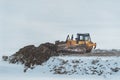 Bulldozer working on road construction site in grading phase in winter time