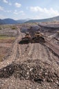 Bulldozers rake gold-bearing mountain soil into a heap