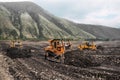 Gold mining industry. Bulldozers rake gold-bearing mountain soil into a heap