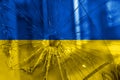 Bullet hole, cracks in the glass on a yellow-blue background. Ukraine flag on broken glass texture. Concept, Russian-Ukrainian war