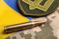 Bullet, Ukrainian flag and military patch on pixel camouflage, closeup