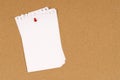 Untidy torn notepaper pinned with thumbtack to a cork notice board background