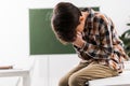 Bullied schoolboy sitting on table covering Royalty Free Stock Photo