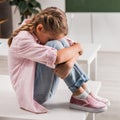 Bullied schoolgirl covering face while sitting Royalty Free Stock Photo