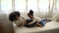 bully african sister girl teased her sister by beating on bed in the bedroom at home . black sibling children unruly . kid annoy