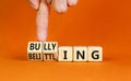 Bullying and belittling symbol. Concept words Bullying and Belittling on wooden cubes. Businessman hand. Beautiful orange table Royalty Free Stock Photo