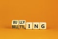 Bullying and belittling symbol. Concept words Bullying and Belittling on wooden cubes. Beautiful orange table orange background. Royalty Free Stock Photo