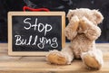 Teddy bear covering eyes and stop bullying text on a blackboard