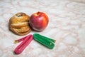 Bun, apple and two measuring tapes. Healthy and unhealthy food concept Royalty Free Stock Photo