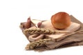 Bun on a cutting board on canvas napkin, ears of wheat and cloves of garlic on white background Royalty Free Stock Photo