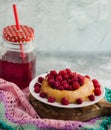 Bun with fresh raspberries on a white plate and red stewed fruit in a glass jar; summer light breakfast for a good mood
