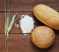 Bun and a loaf of white bread, flour and wheat ears lying on old Royalty Free Stock Photo