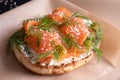 Bun topped with fresh cream, garnished with smoked fish trout and sprinkled with fresh dill and sesame seeds on baking paper