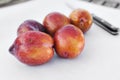 A Bunch of Amigo Pluot Fruit with a Knife in View on White Paper