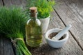 Bunch of aromatic fresh green dill, mortar of fennel seeds and dill oil bottle.