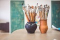 A bunch of art brushes standing in ceramic vases, on the table in the art studio Royalty Free Stock Photo