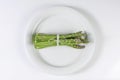 Bunch of asparagus tied with twine on white plate
