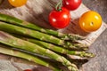 Bunch of asparagus and tomatoes on wooden cutting board Royalty Free Stock Photo