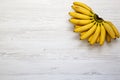 Bunch of baby banana on white wooden background, top view. Royalty Free Stock Photo