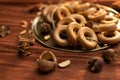 A bunch of bagels lie on a bronze platter, decorated with dried flowers and herbs. On a background of corrugated paper