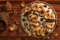 A bunch of bagels lie on a bronze platter, decorated with dried flowers and herbs. On a background of corrugated paper