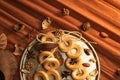 A bunch of bagels lie on a bronze platter, decorated with dried flowers and herbs. On a background of corrugated paper