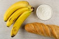 Bunch of bananas, bowl with soft cottage cheese, loaf of bread on table. Top view Royalty Free Stock Photo